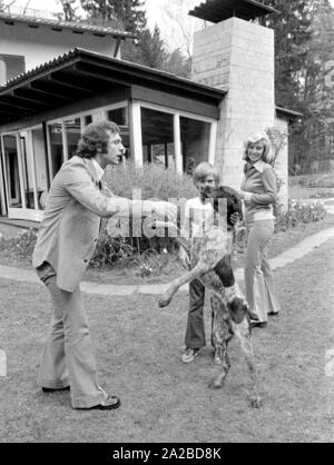 Home Geschichte mit dem Beckenbauer Familie. Im Bild: Franz Beckenbauer (li.), im Garten spielen mit dem Hund. Rechts im Bild, Frau Brigitte Beckenbauer. Etwas versteckt, Sohn Thomas. Stockfoto