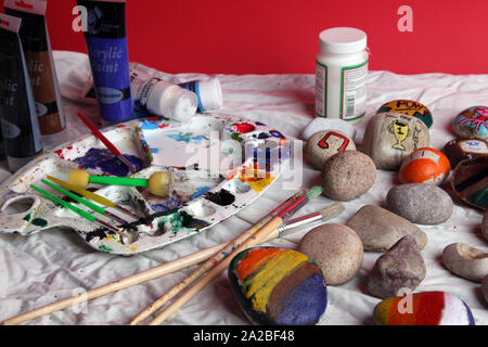 Steine zum Steinmalen auf einem Basteltisch mit Farbe und Pinsel Stockfoto