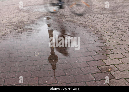 Berlin, Deutschland. 02 Okt, 2019. Eine Pfütze von Regen spiegelt den Fernsehturm und ein Radfahrer. Quelle: Jörg Carstensen/dpa/Alamy leben Nachrichten Stockfoto