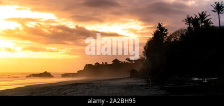 Schwarzer Sandstrand in Nebel und Spray bei Sonnenuntergang abgedeckt Stockfoto