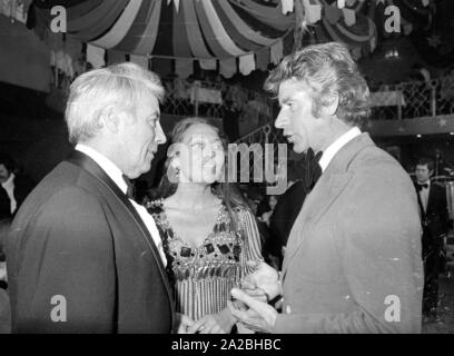 Johannes Heesters (li.) im Gespräch mit Rudi Carrell (r.) und seine Frau Anke Bobbert (m.) An den Deutschen Filmball 1974 im Bayerischen Hof. Stockfoto