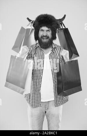 Wunderbare erwerben. Bärtiger Mann lächelnd mit persönlichen erwerben. Happy Hipster in Stier Hörner hat seinen Kauf in paperbags. Kaufen Mode kaufen. Stockfoto