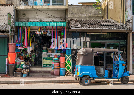 Ein Tuk-Tuk ist außerhalb einer typischen Shop, oder Kade, in Colombo, Sri Lanka geparkt. Stockfoto