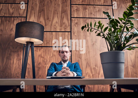 Bild von jungen Brunet im Geschäft, am Tisch sitzen auf dem Hintergrund der hölzernen Wand im Büro Stockfoto