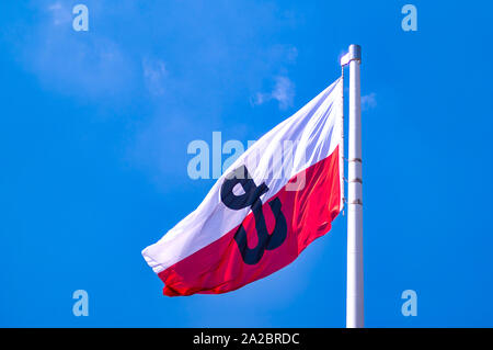 Polen, Warschau: Weiße und rote Flagge der Republik Polen mit dem Emblem des polnischen Untergrundstaates und seiner Heimatarmee. Stockfoto