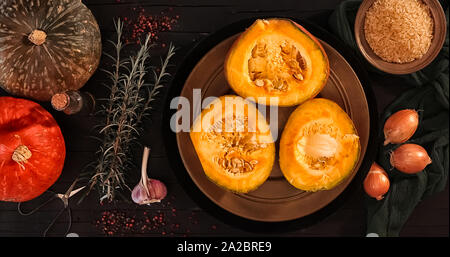 Zutaten für das Risotto mit roten kury Squash fotografiert auf einem schwarzen Holz Tabelle von oben. Stockfoto