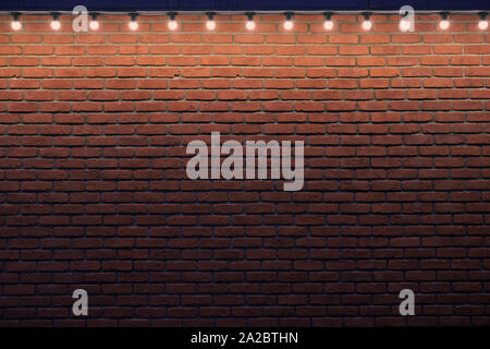 Eine orange brick wall mit kleinen Glühbirnen. Gradient Stein Hintergrund mit wenig Licht und Raum. Für die Anzeige. Stockfoto