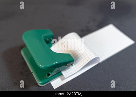 Beachten Sie Papier, Lochen und gegenüber dem Veranstalter. Wirtschaft und Arbeit Konzept. Schreibwaren Notebook mit leeren Seiten. Office Tools auf grauem Hintergrund. Stockfoto