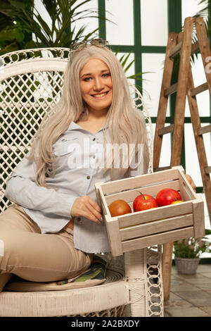 Schöne Mädchen im Gewächshaus stellt unter den Pflanzen und genießt die saubere Luft und die Harmonie der Kommunikation mit der Natur. Stockfoto