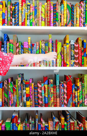 Somerset House, London, Großbritannien, 02. Okt 2019. Ein Assistent wirft mit Yinka Shonibare's Arbeit' der American Library Collection', featurung farbenfrohe afrikanische Drucken abgedeckt Bücher auf seinem Regal. Somerset House, in Partnerschaft mit 1-54, präsentiert die Zeitgenössische Afrikanische Kunst Messe, jetzt in seiner 7. Jahr im Somerset House. Die Messe läuft von Okt 3-6 und vereinigt 45 führende Galerien mit über 140 Künstlern. Credit: Imageplotter/Alamy leben Nachrichten Stockfoto