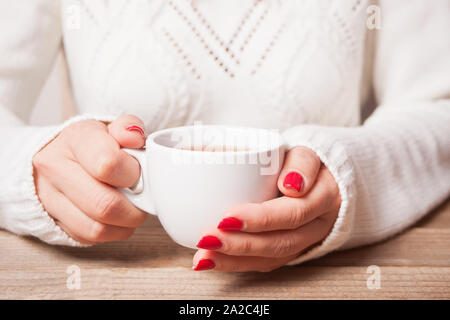 Frau in einem weißen Pullover holding Tasse Tee. Stockfoto