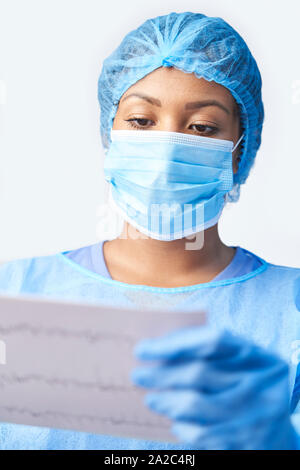 Weibliche Chirurg tragen Kleid und Maske Holding medizinischen Ausdrucken Stockfoto