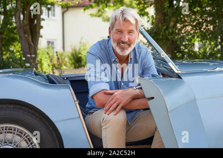 Portrait von Stolz reifer Mann sitzen In restaurierten klassischen Sportwagen im Freien zu Hause Stockfoto