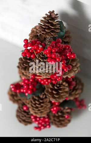 Zarte Tannenzapfen Weihnachtsbaum mit roten Holly Beeren Dekoration Stockfoto