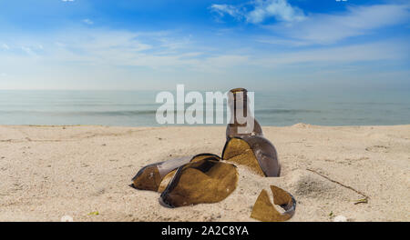 Die Verschmutzung durch eine zerbrochene Glasflasche liegen am Strand im Sand Stockfoto