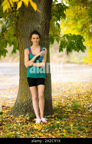 Junge Frau ruhen Sie sich nach einen langen Lauf im Wald an einem schönen sonnigen Herbsttag Stockfoto