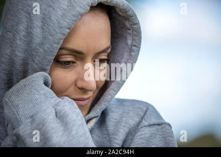 Junge Frau an einem kalten Morgen in ein Kapuzenshirt vor dem ausgehen für einen Lauf Stockfoto