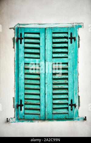 Rustikale Außenfenster mit geschlossenen Holzbrett Fensterläden in türkis grün Stockfoto