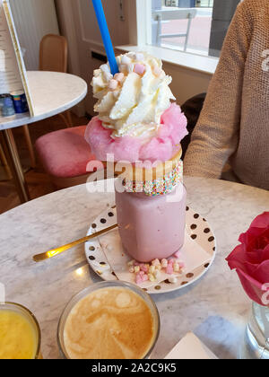 Rosa Erdbeere freakshake mit Süßigkeiten, Donuts und wipped Cream im Cafe, extreme Milchshake Stockfoto