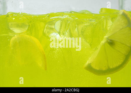 Nahaufnahme der Zitronenscheiben in Limonade Hintergrund. Textur der Kühlung's Sweet Summer Drink mit Makro Blasen an der Glaswand. Zischenden oder schwimmend auf der Oberfläche nach oben. Stockfoto