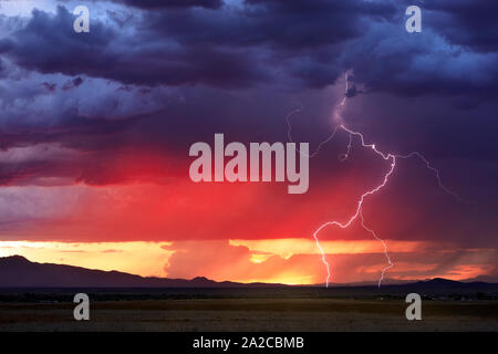 Monsunblitze treffen in einem farbenfrohen Sonnenuntergangshimmel ein, während sich ein Gewitter von den Bradshaw Mountains in der Nähe von Prescott, Arizona, absetzt Stockfoto