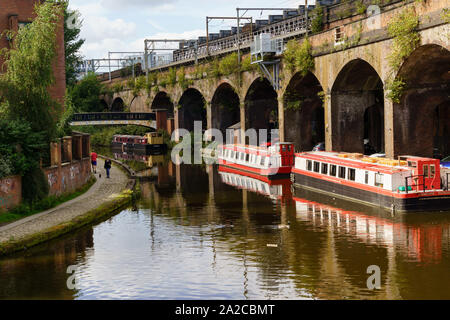 Bridgewater Canal mit Bargen, die neben einem viktorianischen Eisenbahnviadukt vertäut sind, Castlefield Basin, Greater Manchester, England, Großbritannien. Stockfoto