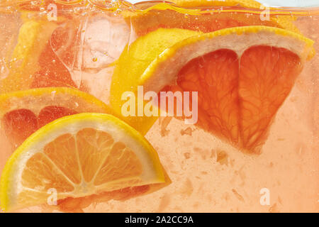 Nahaufnahme der Zitrone und Grapefruit Schichten in Limonade Hintergrund. Textur der Kühlung's Sweet Summer Drink mit Makro Blasen an der Glaswand. Zischenden oder schwimmend auf der Oberfläche nach oben. Stockfoto