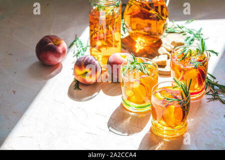 Gläser süßer Pfirsich Eistee, Sommer kalt Pfirsich fizz Cocktail mit Rosmarin. Sonnigen Licht. Geringe Tiefe des Feldes, Nahaufnahme, kopieren Sie Raum für Sie Stockfoto