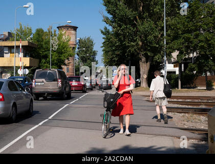 Die Frau im roten Kleid mit Fahrrad überqueren Bahngleise, Tallinn, Estland Stockfoto