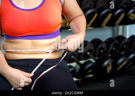 Fette Frau Hand übermäßiges Bauchfett mit Maßband. Diät, Gewichtsverlust, schlanken Körper, gesunde Lebensweise Konzept. Stockfoto