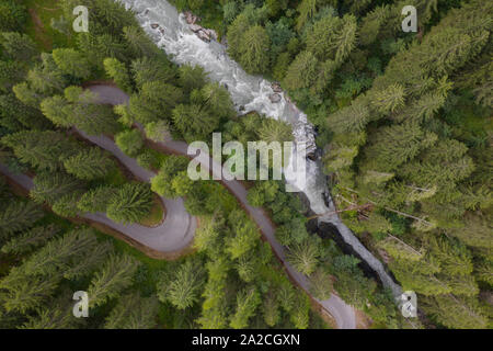 Foto mit einer Drohne über eine S-förmige Straße in einem Nadelbaum fliegen und einen Wasserfall in einem weichen Atmosphäre genommen Stockfoto