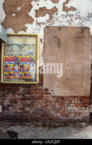 Alten zerrissenen Poster Förderung ein Karneval in die Stadt kommen. Auf alten Ziegelmauer mit abblätternder Farbe. Tipton, nordwestlich von Birmingham, West Midlands, UK. Stockfoto