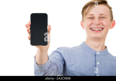 Happy teenager Boy mit seinem Smartphone leeren Bildschirm auf weißem Hintergrund. Freudige jugendlichen Kerl präsentiert ein neues Gerät. Stockfoto