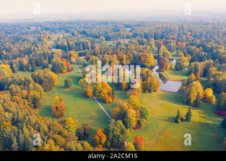 Luftaufnahme Flug über Herbst Valley Park mit Wiesen und einen gewundenen Fluss, Teiche, helle Bäume Stockfoto