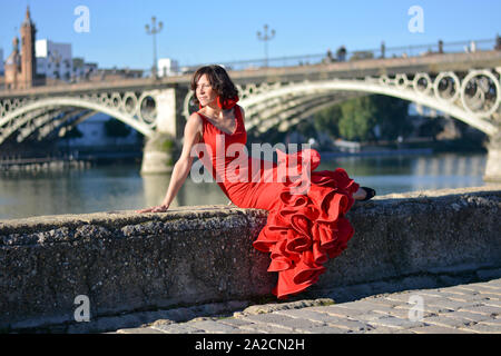 Das Mädchen sitzt auf der Kante des Guadalquivir, in Sevilla, in dem beliebten Viertel Triana Stockfoto