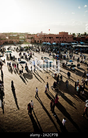 Blick auf den Platz Jamaa el Fna in Marrakesch von oben bei Sonnenuntergang, mit vielen Touristen und langen Schatten, die entlang des Platzes ragen Stockfoto