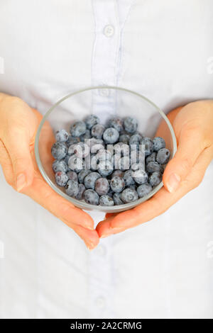 Nahaufnahme von Frau Hände halten eine Glasschüssel frische Heidelbeeren Stockfoto