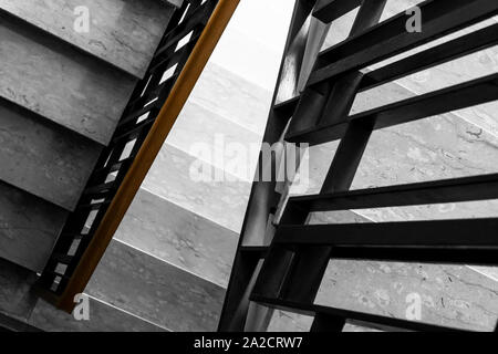 Treppen im Wohngebäude, mit Holzgeländer. Die Stufen sind aus weißem Marmor mit schmaler Struktur Stockfoto