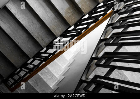 Treppen im Wohngebäude, mit Holzgeländer. Die Stufen sind aus weißem Marmor mit schmaler Struktur Stockfoto