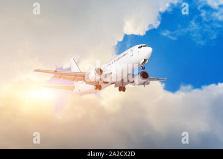 Flugzeug fliegen aus den Wolken sunset orange sky. Stockfoto