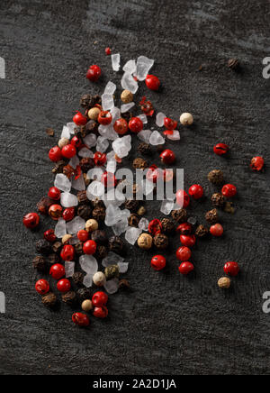 Rot, Weiß und plack Pfefferkörner mit großen Salz auf einem dunklen Groll Holz Hintergrund Stockfoto