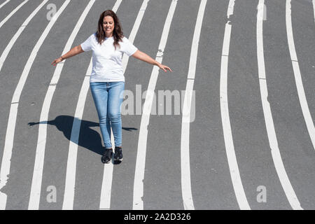 Frau Balancieren auf eine weiße Linie auf den Boden gemalt. Stockfoto