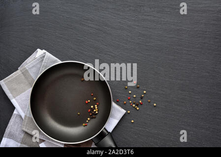 Leere Pfanne mit Serviette und mix Paprika auf dunklen grauen Stein Hintergrund. Ansicht von oben Stockfoto