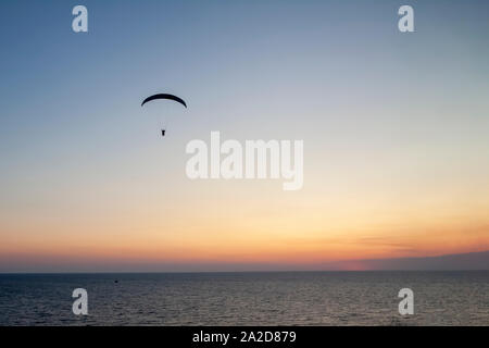 Gleitschirm mit einem Mann hoch in den blauen Himmel gegen die untergehende Sonne. Stockfoto