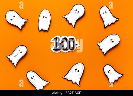 Spooktacular Halloween Geister fliegen auf orangefarbenem Hintergrund Stockfoto