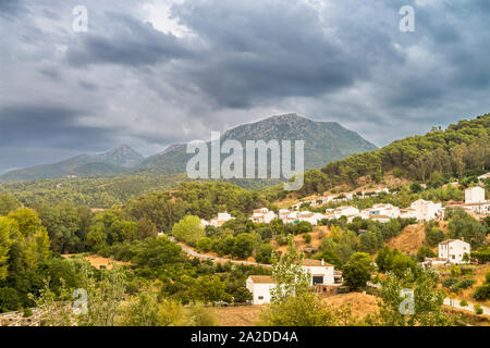 Landschaft, in der Sie eine kleine Stadt an einem Berghang sitzen sehen können, mit einem bewölkten Himmel im Hintergrund. Stockfoto