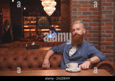 Junge bärtige Mann allein sitzen im Cafe. Stockfoto