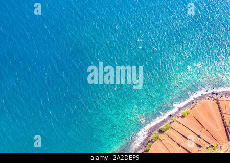 Luftaufnahmen der Atlantik Küste. Stein Strand und die angrenzenden Felder an der Südküste der Insel Madeira in der rechten unteren Ecke. Luftaufnahme, Seascape. Erstaunlich portugiesische Insel. Stockfoto