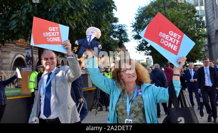 Konferenzteilnehmer, die die Konservative Party Conference 2019 in Manchester verlassen, tragen am letzten Tag Schilder mit dem Titel „Get Brexit Done“, ein Hauptthema der Konferenz, und eine Boris Johnson-Puppe, die an Demonstranten vorbei war. Stockfoto