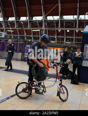 Juni 2016 - Mann am Bahnhof Paddington in London mit seinem Brompton Faltrad Stockfoto